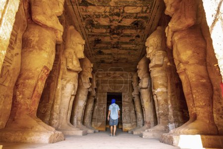 A young tourist looking at the pharaohs at the Abu Simbel Temple in southern Egypt in Nubia along Lake Nasser. Temple of Pharaoh Ramses II, travel lifestyle