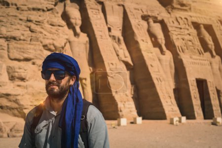 A young man wearing a blue turban visiting the Egyptian Temple of Nefertari near Abu Simbel in southern Egypt in Nubia next to Lake Nasser. Temple of Pharaoh Ramses II, travel lifestyle