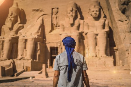 A young tourist in a blue turban looking at the Abu Simbel Temple in southern Egypt in Nubia next to Lake Nasser. Temple of Pharaoh Ramses II, travel lifestyle