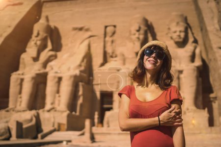 A young tourist in red dress at the Abu Simbel Temple in southern Egypt in Nubia next to Lake Nasser. Temple of Pharaoh Ramses II