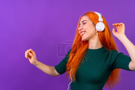 Redhead woman in studio photography dancing on a purple background