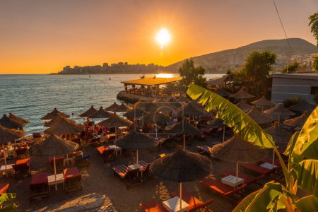 Schöne Ferienanlage mit Sonnenschirmen am Meer bei Sonnenuntergang in Sarande oder Saranda an der albanischen Riviera, Albanien