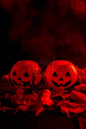 Foto de Calabazas de Halloween en hojas de otoño con humo sobre un fondo rojo - Imagen libre de derechos