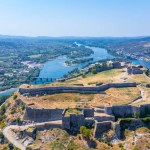 Aerial drone view of Rozafa Castle in the city Shkoder and its walls next to the lake and the river. Albania