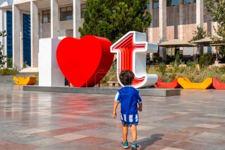 Téléchargez les photos : Un enfant dans la sculpture I Love Tirana sur la place Skanderbeg à Tirana réfléchit. Albanie - en image libre de droit