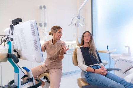 Foto de Dentista y paciente hablando sobre el tratamiento en una clínica mientras mira una pantalla - Imagen libre de derechos