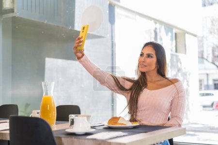 Téléchargez les photos : Beauté décontractée Femme d'affaires prenant un selfie tout en prenant le petit déjeuner dans un hôtel de luxe le matin - en image libre de droit