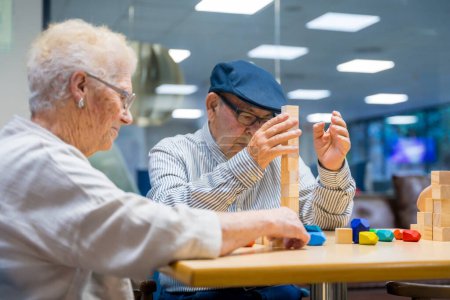 Téléchargez les photos : Paire de personnes âgées dans une maison de soins infirmiers jouant à des jeux d'adresse - en image libre de droit