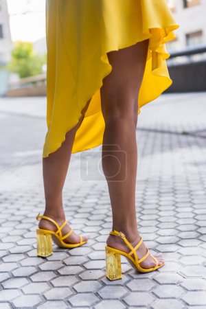 Photo for Vertical cropped photo of the sensual legs of a woman wearing yellow dress heels - Royalty Free Image