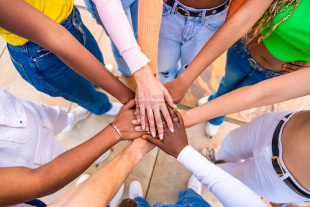 Photo for Top view close-up photo of multi-ethnic young people joining hands in a huddle - Royalty Free Image