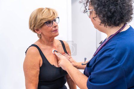 Photo for Female doctor putting woman with heart problems undergoing ECG Holter monitor test with innovative device - Royalty Free Image