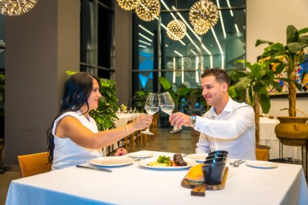 Photo for Couple toasting with white wine during a dinner in a luxury restaurant - Royalty Free Image