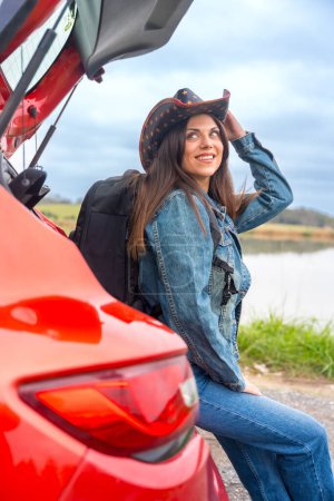 Téléchargez les photos : Portrait vertical d'un voyageur sensuel détendu lors d'un road trip avec une voiture rouge - en image libre de droit