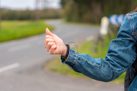 Téléchargez les photos : Photo en gros plan de la main d'une femme en stop sur une route rurale - en image libre de droit