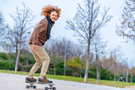 Photo for Skater with curly redhead hair on a board in an urban park - Royalty Free Image