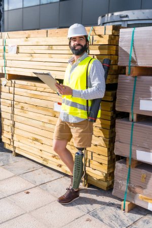 Photo for Vertical portrait of a smiley engineer with amputee leg working in a construction site - Royalty Free Image