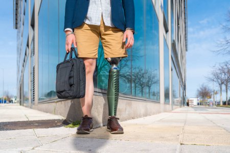 Téléchargez les photos : Partie inférieure d'un homme d'affaires méconnaissable avec une prothèse de jambe debout dans la ville - en image libre de droit
