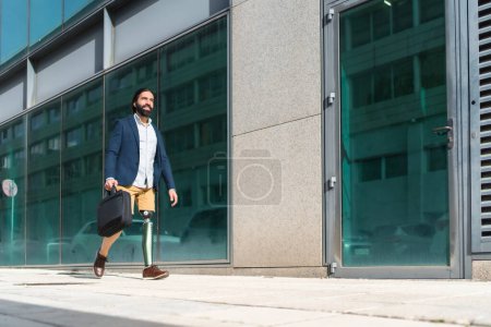Photo for Photo with copy space of a businessman with prosthetic leg walking along a financial district street - Royalty Free Image