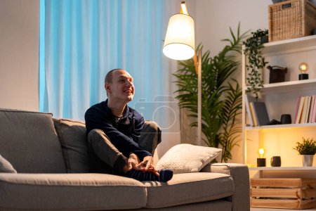 Téléchargez les photos : Portrait avec espace de copie d'un homme handicapé se sentant seul assis sur le canapé à la maison la nuit - en image libre de droit