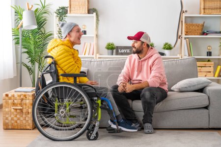 Behinderter im Rollstuhl und Freunde plaudern entspannt im Wohnzimmer des Hauses