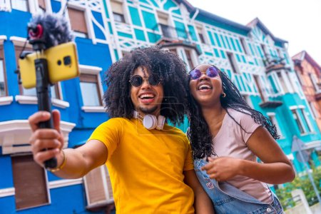 Young african casual content creators recording an online video in a colorful neighborhood