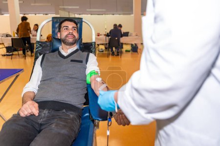Téléchargez les photos : Homme et infirmière parlent calme dans un centre de don de sang pendant l'extraction du sang - en image libre de droit