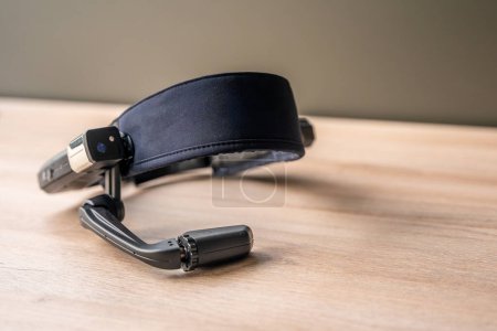 Téléchargez les photos : Casque avec microphone en plus des lunettes futuristes de réalité mixte sur une table en bois - en image libre de droit