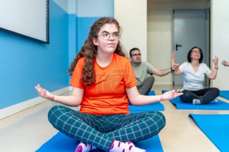 Fokus auf eine behinderte Frau in Lotusposition während eines Yoga-Kurses neben Freunden