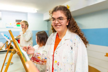 Portrait d'une femme handicapée souriant pendant les cours de peinture à l'intérieur