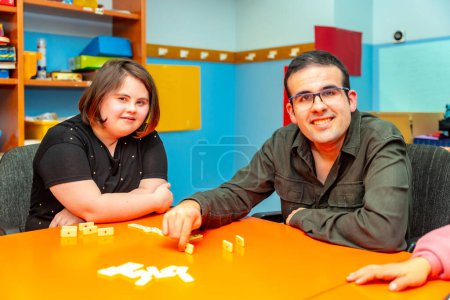 Two people with special needs distracted playing board games sitting on a table in a day center