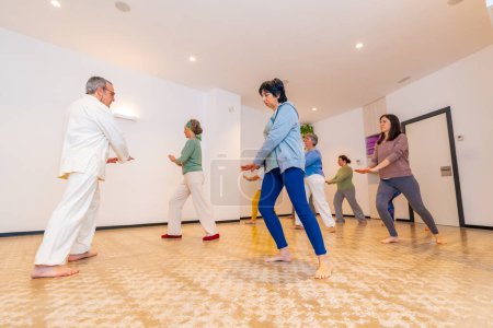 Qi gong male instructor leading a wi gong session class with mature and adult caucasian women