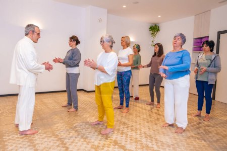 Qi-Gong-Instruktor und Frauen schließen Augen und atmen während eines Indoor-Kurses