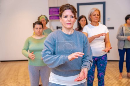 Frontal portrait of a group of caucasian adult concentrated women in a Qi gong classroom