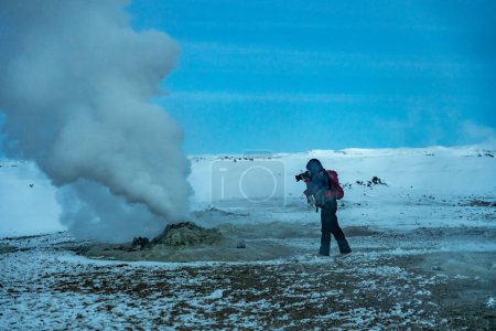 Abenteuerlustige Fotografin im Winter in Island beim Fotografieren im geothermischen Gebiet von Hverir oder Namafjall