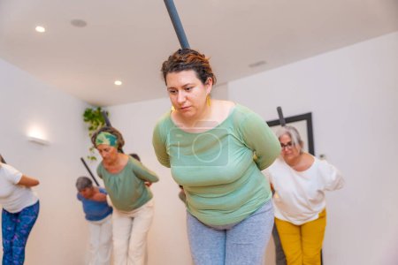 Women stretching the back helped by a tube in a qi gong class