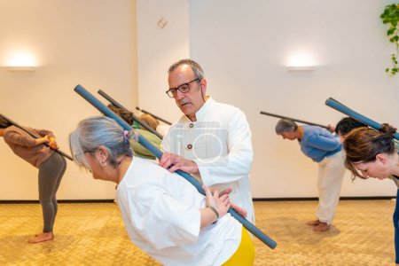 Qi-Gong-Kursteilnehmer dehnen den Rücken mit einem Schlauch unter Anleitung eines männlichen Instruktors
