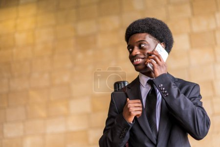 Porträt im Tiefflug mit Kopierraum eines lächelnden afrikanischen Architekten im Gespräch mit dem Mobiltelefon in der Stadt