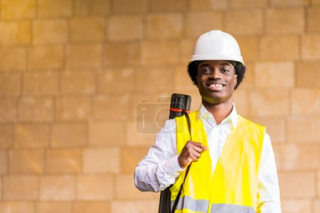 Portrait of a young african architect with protective hard hat and reflective waistcoat in a construction site