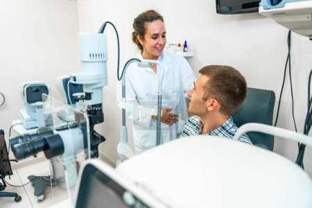 Optométriste féminine parlant avec un patient masculin à la clinique