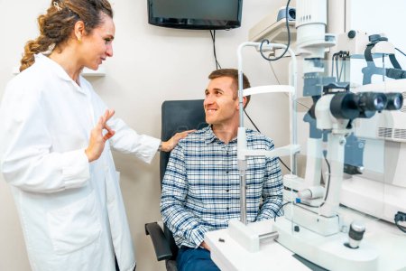 Foto de Doctora y paciente hablando y sonriendo en clínica oftalmológica - Imagen libre de derechos