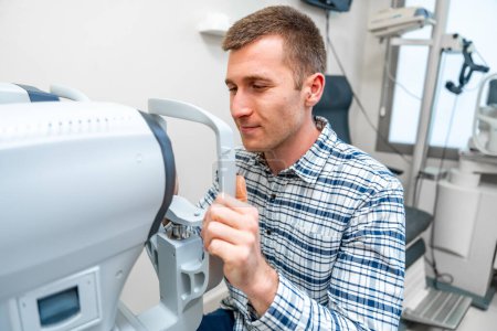 Homme tenant les poignées d'un scanner oculaire dans une clinique d'ophtalmologie