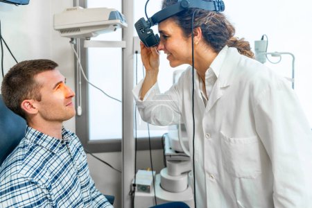 Foto de Oftalmóloga que revisa la retina de un paciente usando la luz de un retinoscopio - Imagen libre de derechos