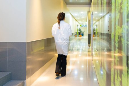 Vue arrière d'une ophtalmologiste marchant le long d'un couloir de la clinique