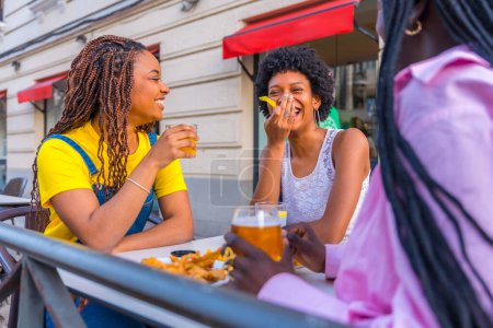 Junge afrikanische Schönheitsfreunde beim gemeinsamen Essen in einem Outdoor-Restaurant