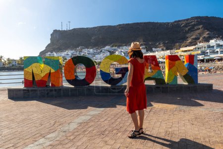 Eine Frau auf dem Touristenschild in der Küstenstadt Mogan im Süden Gran Canarias. Spanien