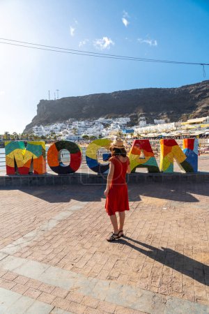 Une femme en robe rouge sur le panneau touristique de la ville côtière de Mogan dans le sud de Gran Canaria. Espagne
