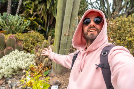 Un touriste souriant appréciant dans un jardin botanique tropical avec de nombreux captus