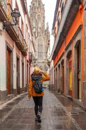 Foto de Una turista con sombrero paseando por una bonita calle junto a la Iglesia de San Juan Bautista, Catedral de Arucas, Gran Canaria, España. - Imagen libre de derechos