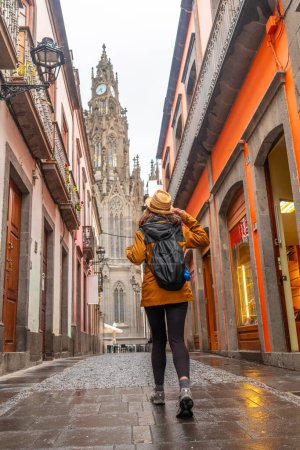 Foto de Una turista caminando por una hermosa calle junto a la Iglesia de San Juan Bautista, Catedral de Arucas, Gran Canaria, España. - Imagen libre de derechos
