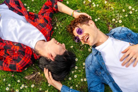 Photo for Top view of a multiracial gay couple enjoying spring lying on a park together - Royalty Free Image